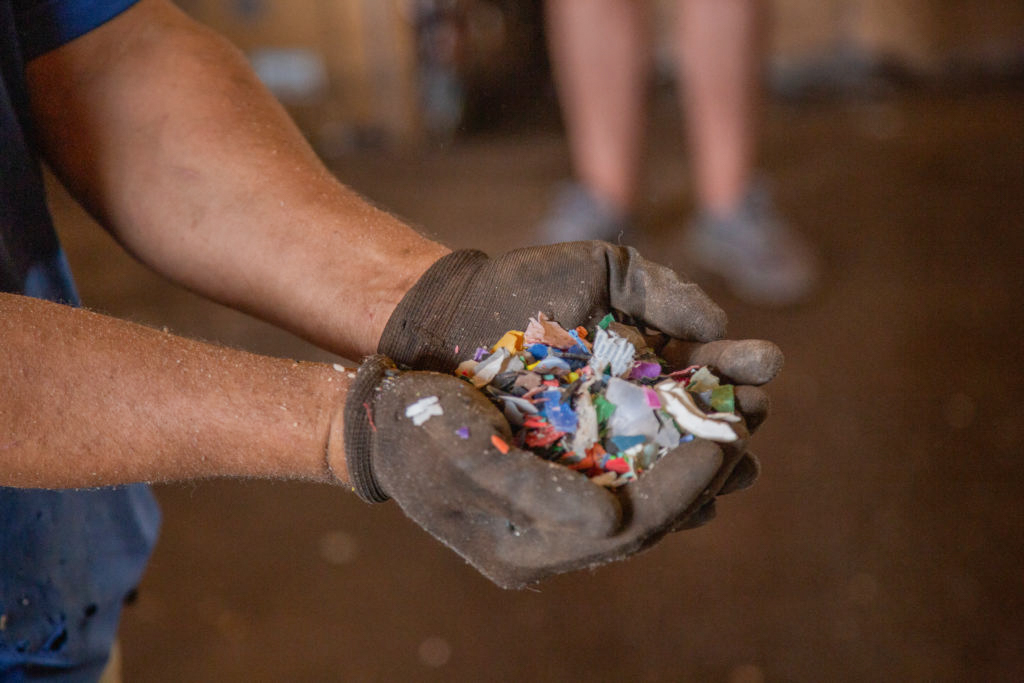 flakes moídos coloridos sendo mostrados diretamente na área de produção industrial da Berpram ambiental